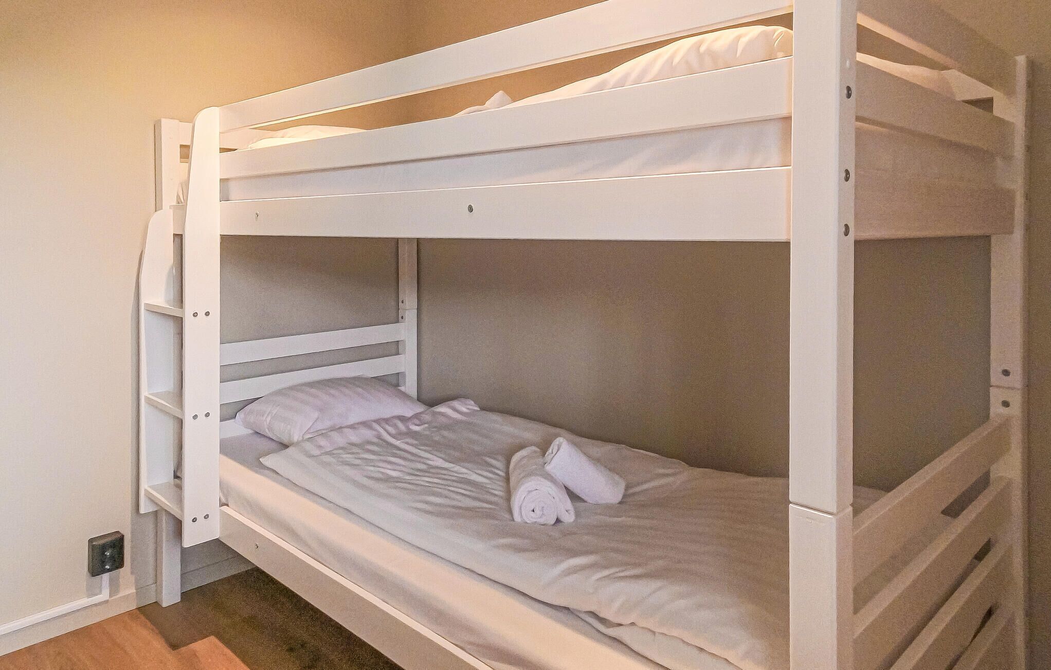 Een stapelbed met een wit frame en één matras.