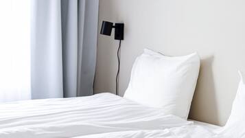Un lit bien fait, avec du linge de lit blanc, dans une chambre d’hôtel.