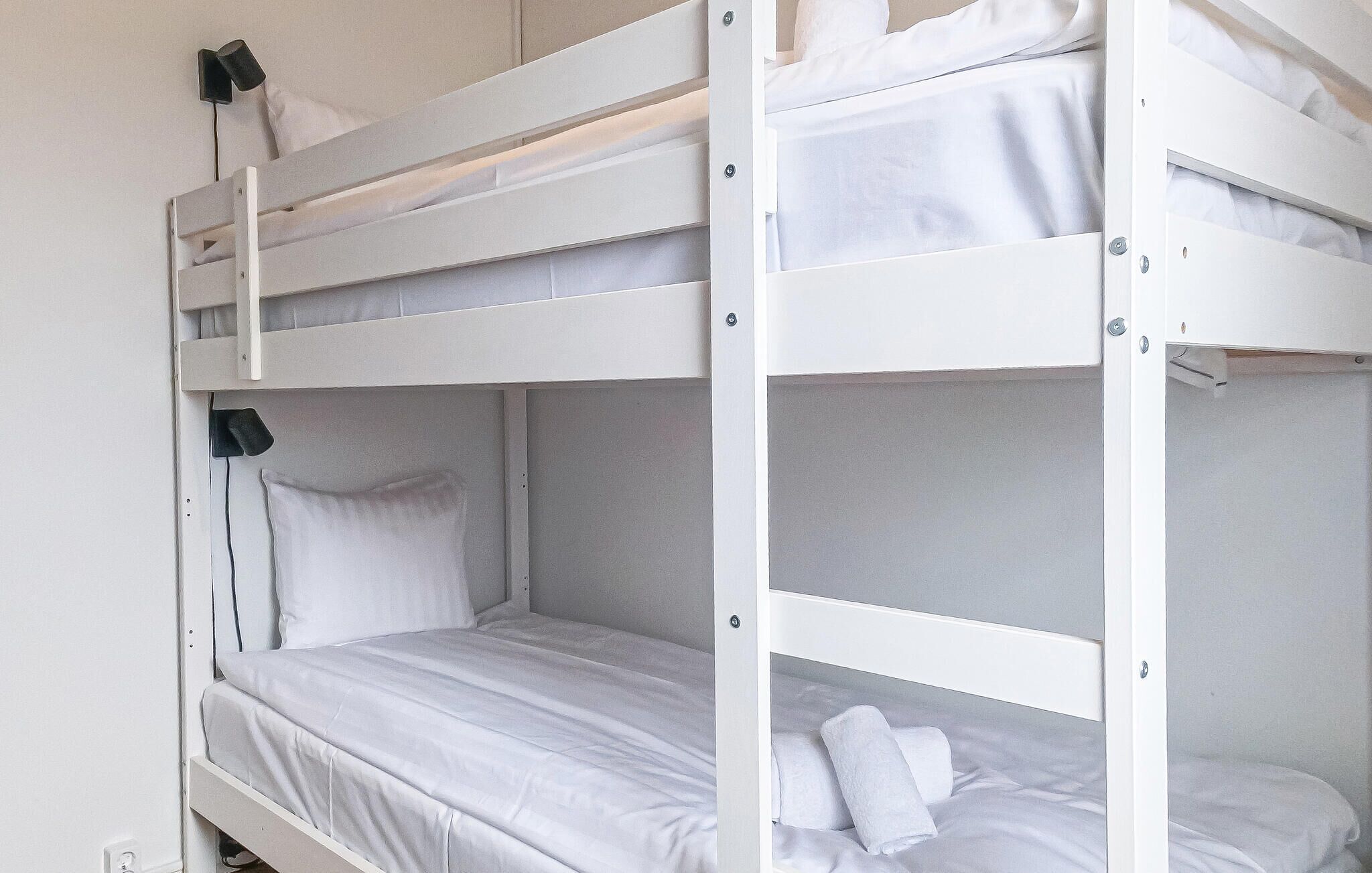 Ein Etagenbett mit weißer Bettwäsche und einem schwarzen Kopfteil.