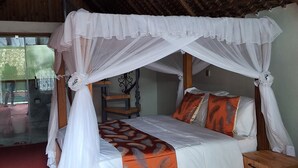 A bed with a canopy, wooden headboard, and pillows with orange and white patterns. - The Giraffe Cottages Restaurant and Bar (Nairobi)