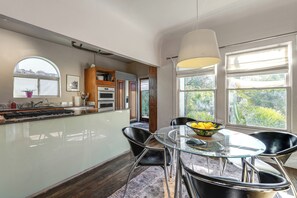 A modern kitchen with a central island, black chairs, and a glass table with a bowl of fruit. - 2 Mi to Downtown: Pet-friendly Home in Phoenix! (Phoenix)