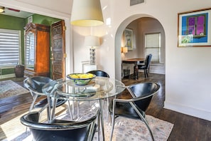 A dining area with a glass table, black chairs, and a bowl of fruit. There is a lamp, a painting, and a window with blinds. - 2 Mi to Downtown: Pet-friendly Home in Phoenix! (Phoenix)