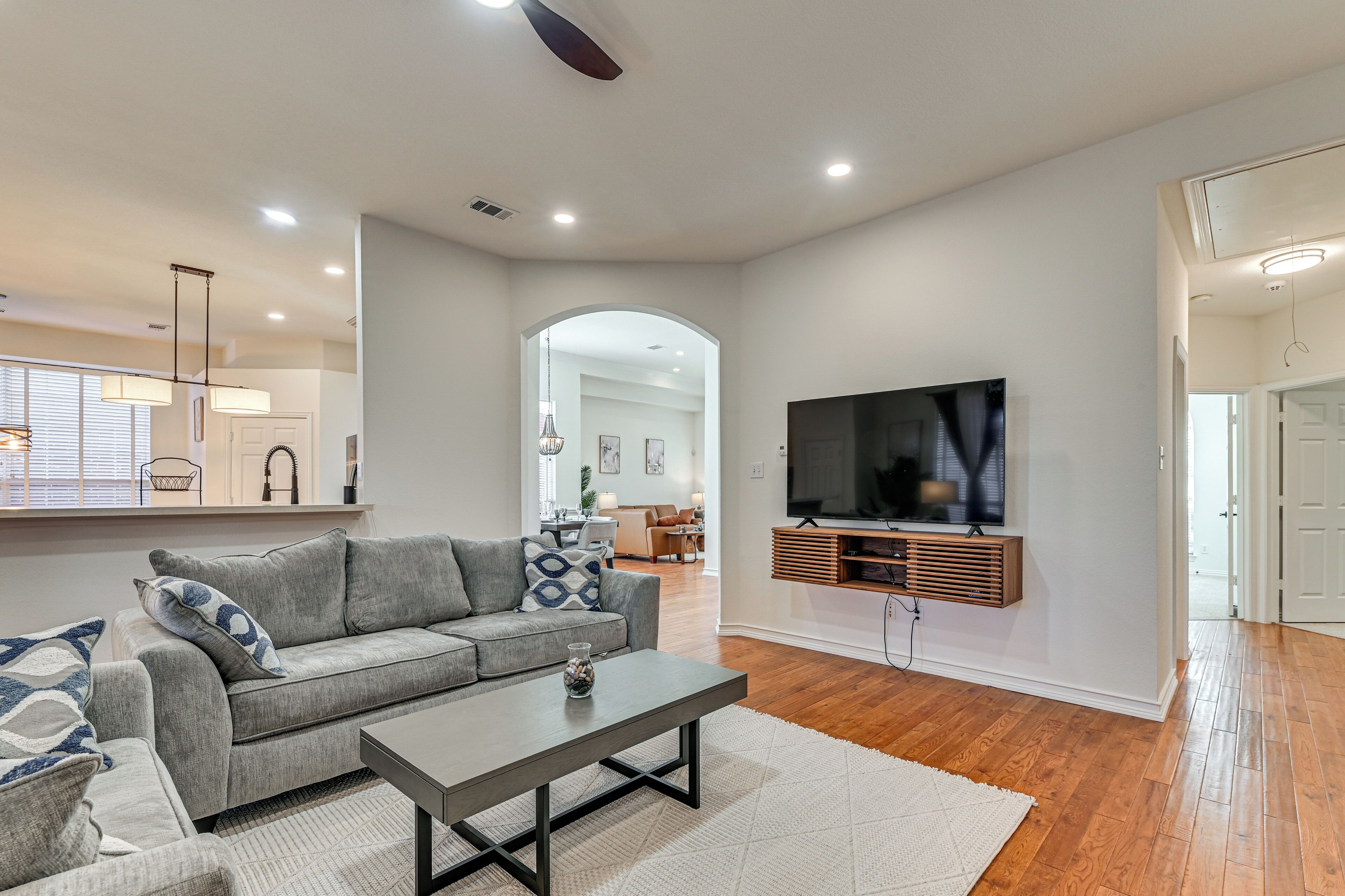 A modern living room with a grey sofa, a coffee table, and a flat-screen TV mounted on the wall.