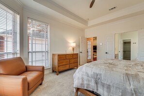 Un dormitorio con una cama grande, un sofá de cuero marrón, un aparador de madera y una puerta que da a otra habitación.