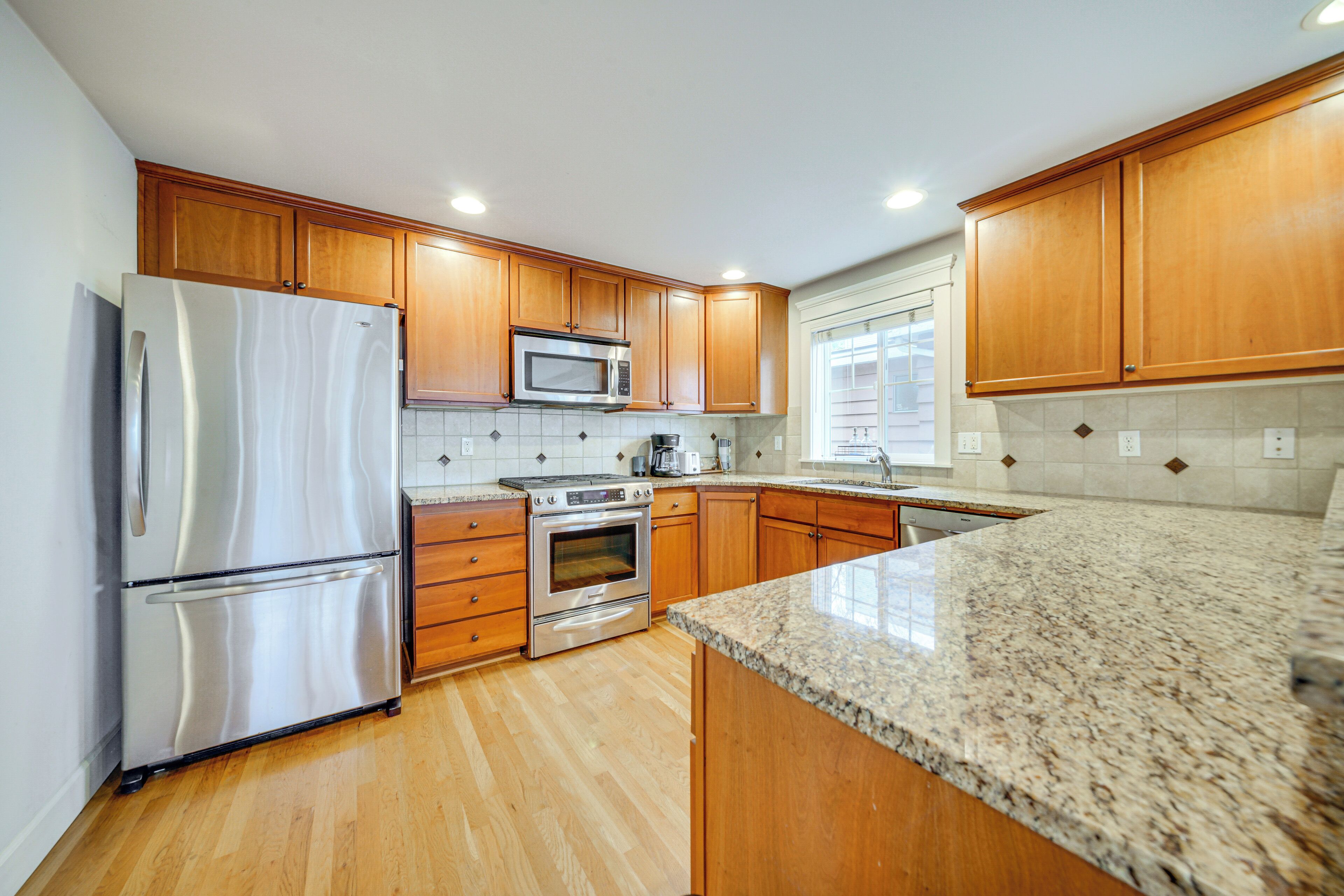 A kitchen with wooden cabinets, stainless steel appliances, and a granite countertop.