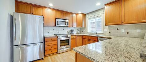 A kitchen with wooden cabinets, stainless steel appliances, and a granite countertop.