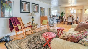 A spacious living room with a large sofa, a coffee table, and a dining area with chairs and a table. - Shop, Dine & Explore: Home 3 Mi to NRG Stadium (Houston)