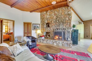 Uma sala de estar acolhedora com lareira de pedra, um sofá, uma mesa de centro e um tapete.