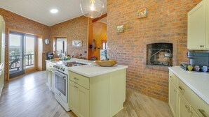 A kitchen with a brick wall, wooden beams, a large island, and a fireplace. - Views of 4 Mtn Peaks! Stunning Scottsdale Oasis (Scottsdale)