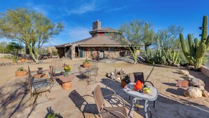 A patio with outdoor furniture, a stone building, and cacti. - Views of 4 Mtn Peaks! Stunning Scottsdale Oasis (Scottsdale)