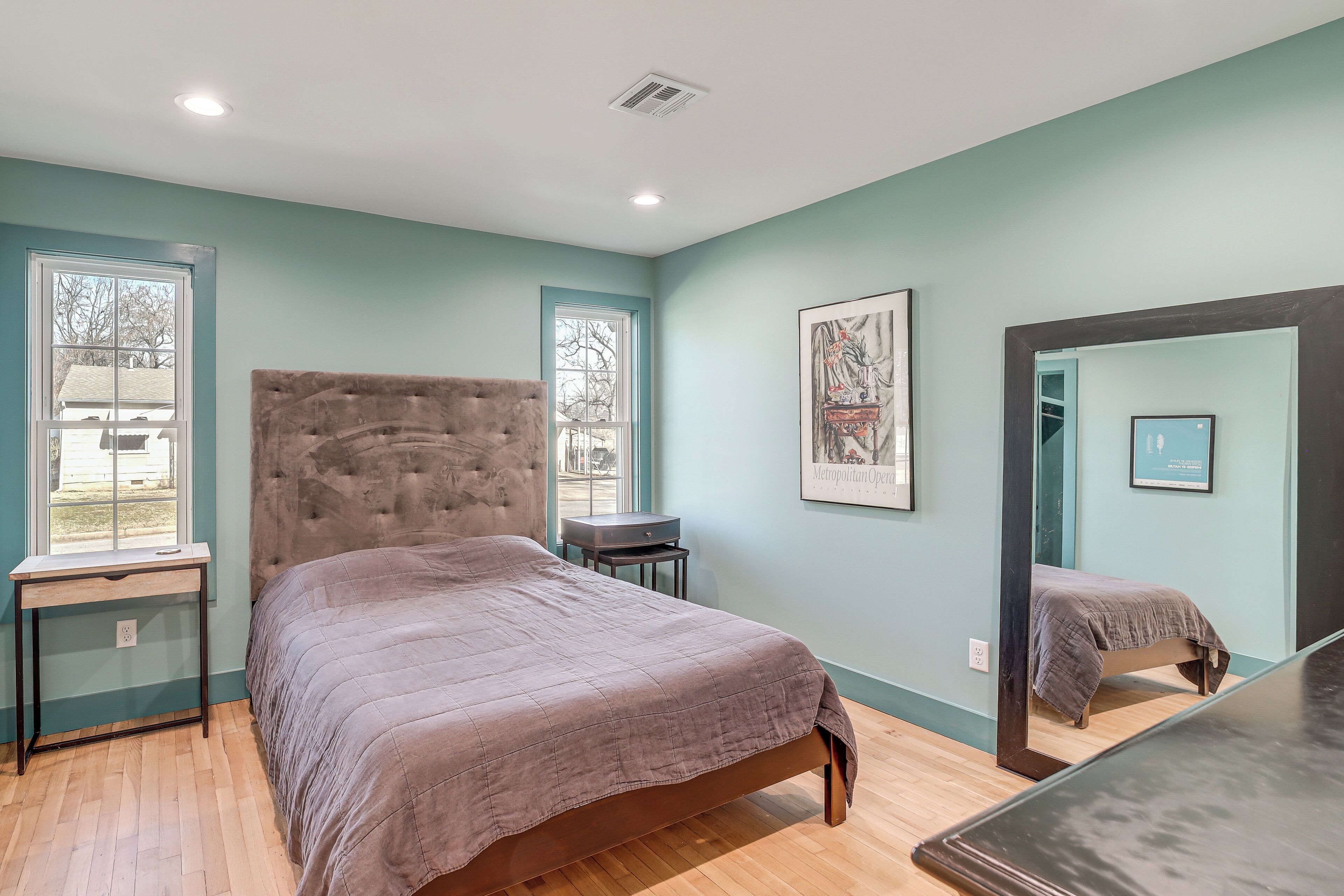 A bedroom with a large bed, a desk, and a mirror.