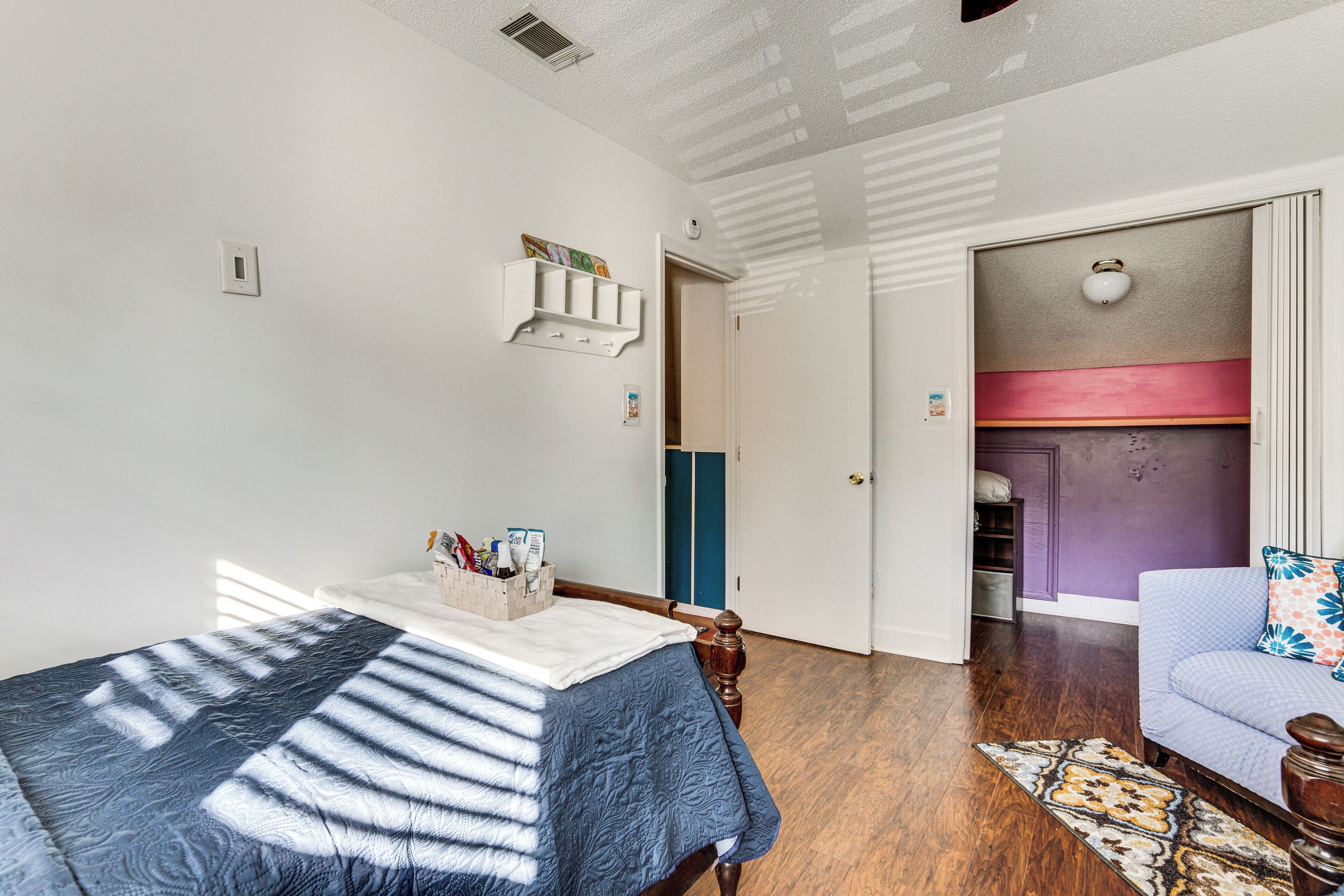 Une chambre à coucher comprenant un lit, une table de chevet, une commode, une coiffeuse et une porte donnant sur une autre pièce.