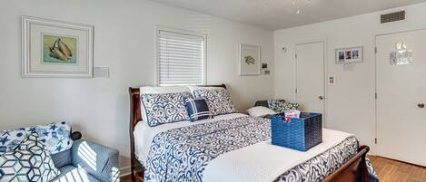 A bedroom with a bed, a chair, a ceiling fan, and wall decorations.