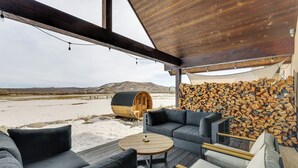 A cozy outdoor seating area with a wooden table, sofas, and a log wall. - Fish, Hike & Ski: Mtn-view Gunnison Home w/ Sauna (Gunnison)