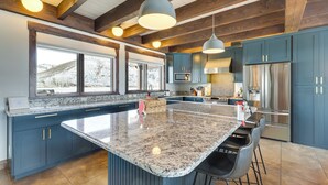 A spacious kitchen with a large island, dark blue cabinets, stainless steel appliances, and pendant lighting. - Fish, Hike & Ski: Mtn-view Gunnison Home w/ Sauna (Gunnison)