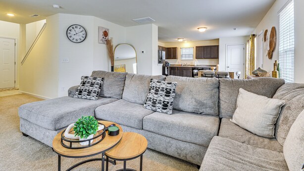 Ein modernes Wohnzimmer mit einer Eckcouch, einem Couchtisch und einer Küche im Hintergrund.