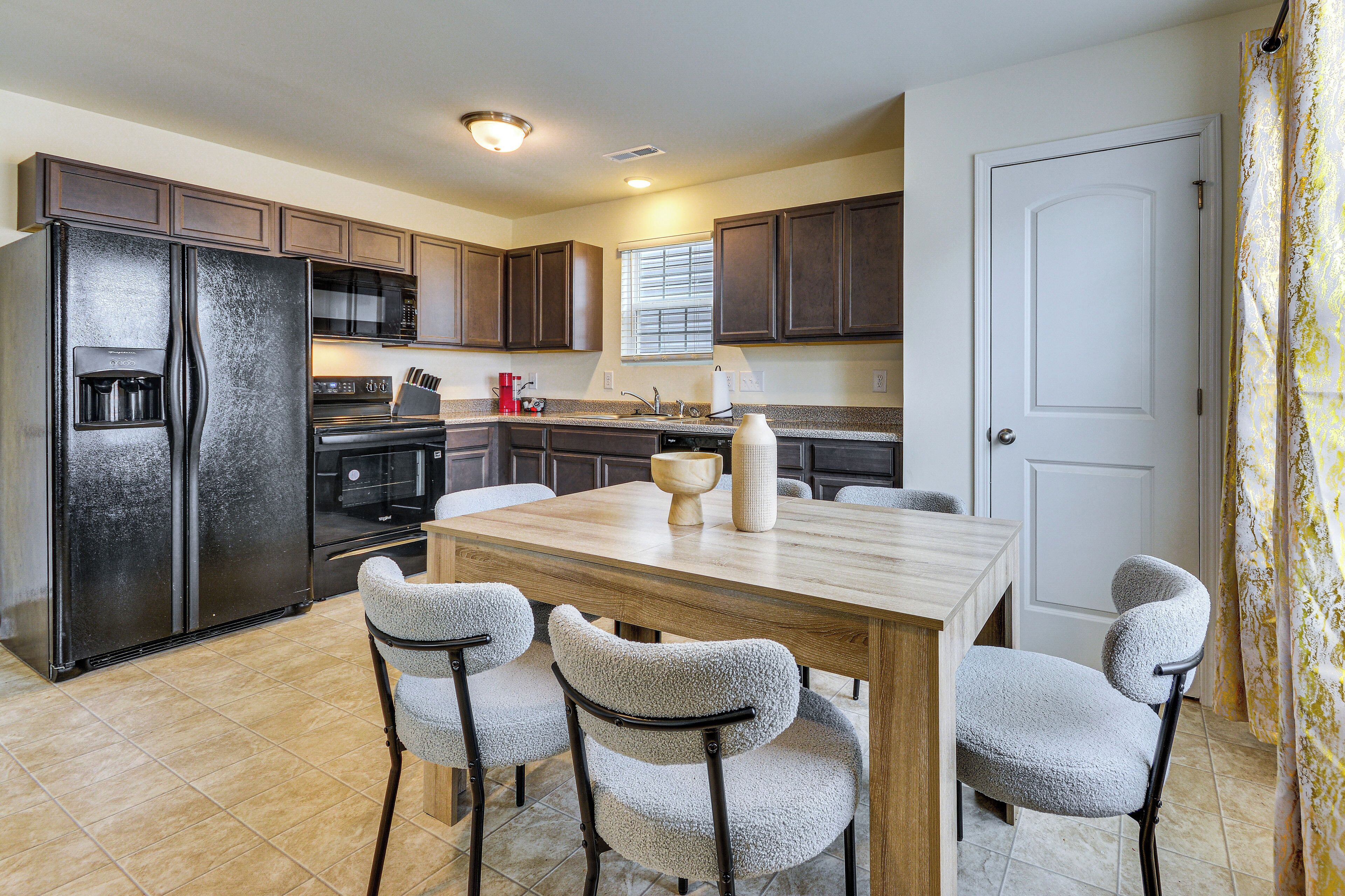 A kitchen with a refrigerator, microwave, stove, and a dining table with four chairs.