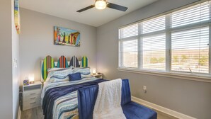 A bedroom with a bed, a ceiling fan, a window with blinds, and a painting on the wall. - Surfboard-themed Huddleston Studio w/ Beach Access (Huddleston)