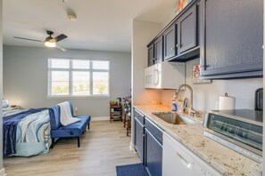 A modern kitchen with dark cabinets, a microwave, and a stainless steel sink. - Surfboard-themed Huddleston Studio w/ Beach Access (Huddleston)