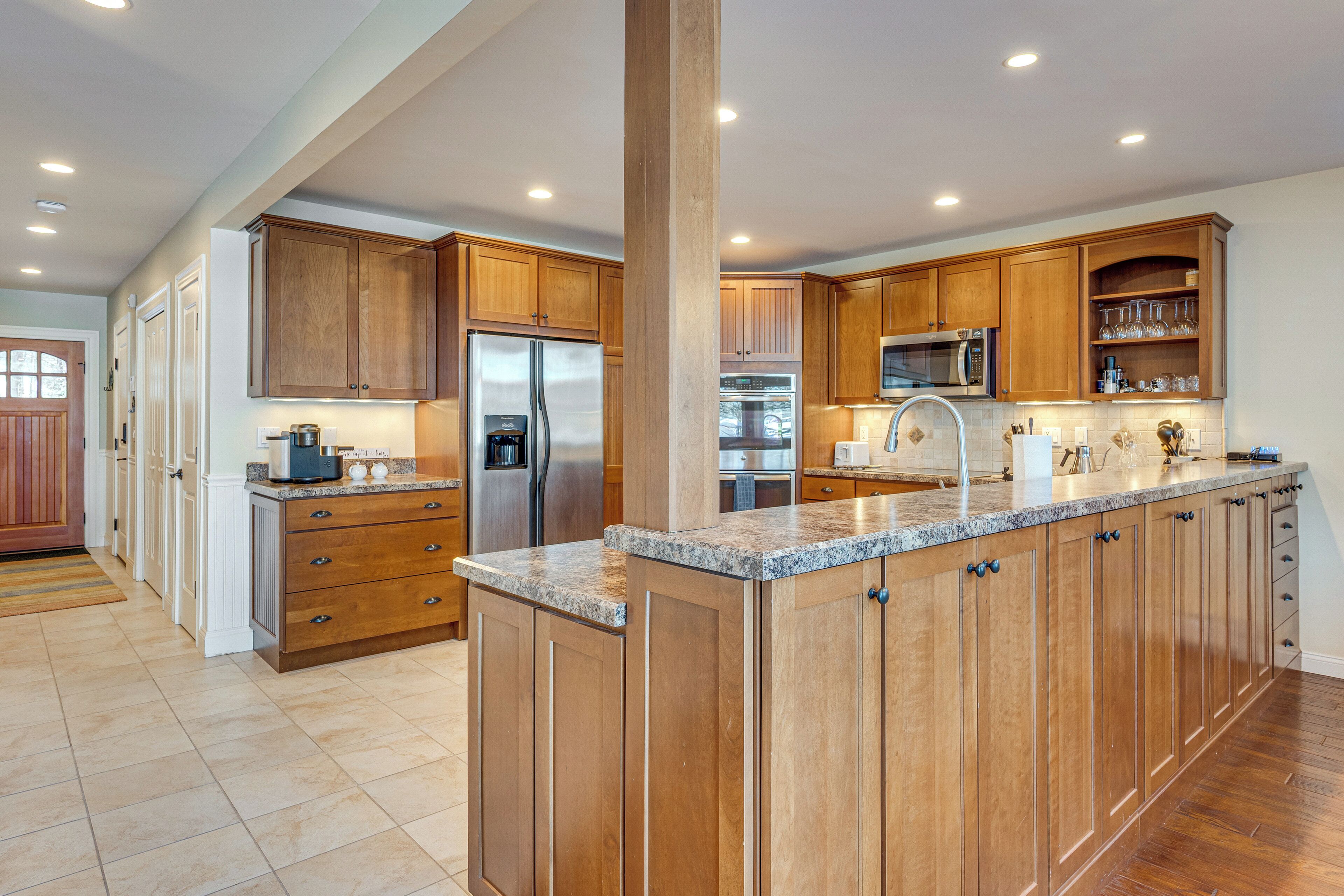 A spacious kitchen with wooden cabinets, a stainless steel refrigerator, a microwave, and a large island with a granite countertop.