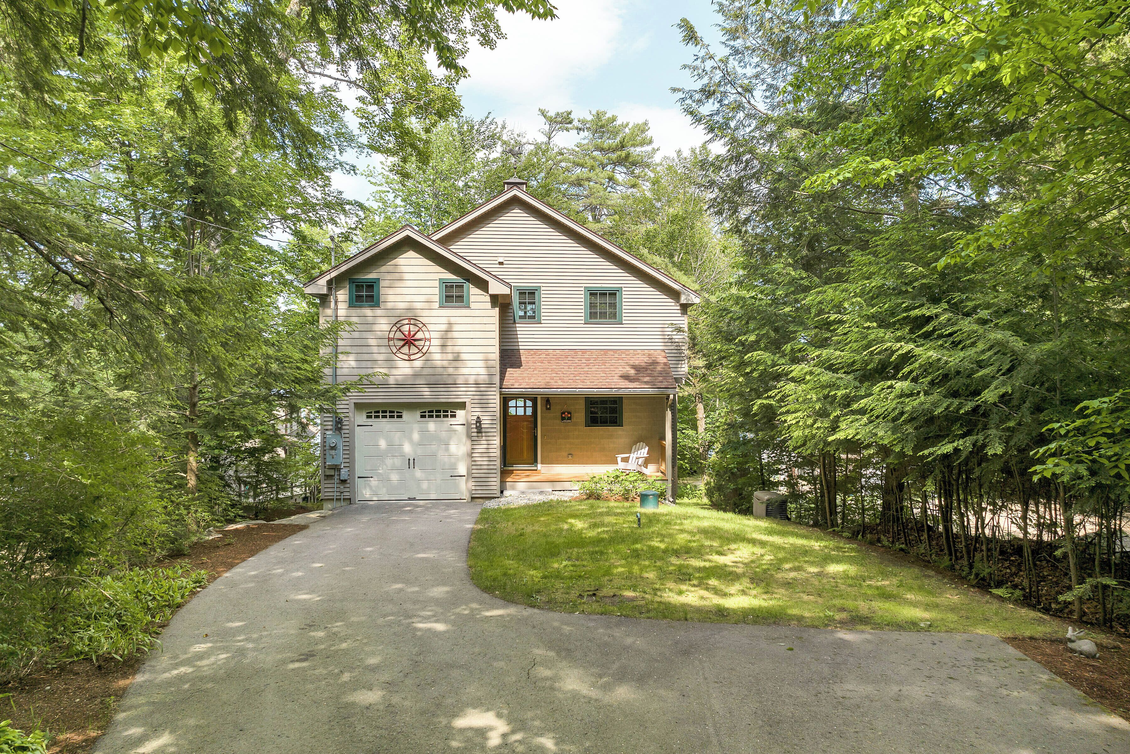 A two-story house with a garage, surrounded by trees and a driveway.