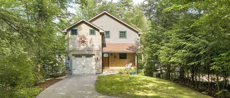 A two-story house with a garage, surrounded by trees and a driveway.