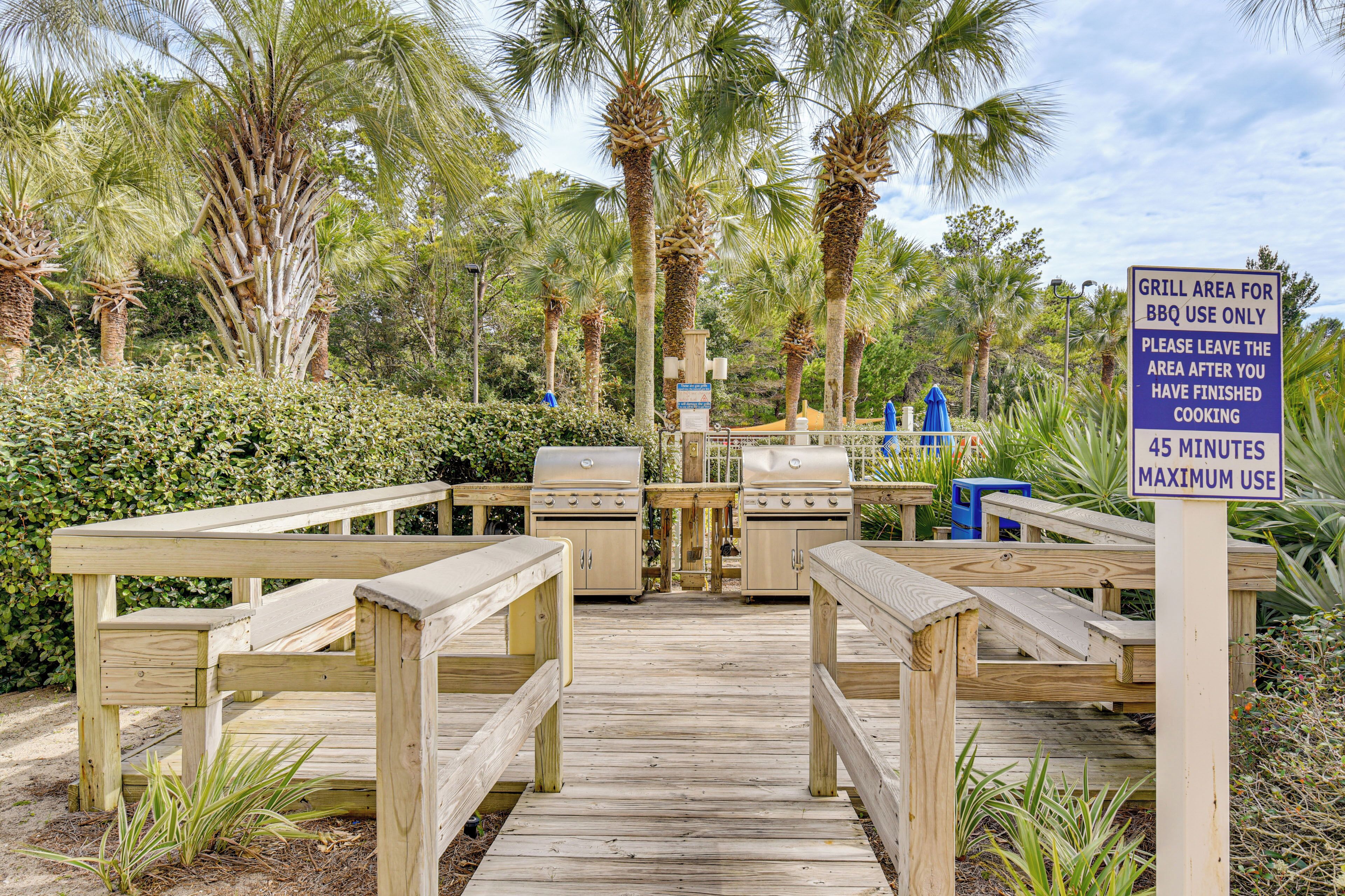A wooden deck with barbecue grills and picnic tables.