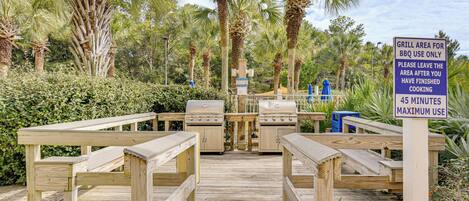 A wooden deck with barbecue grills and picnic tables.