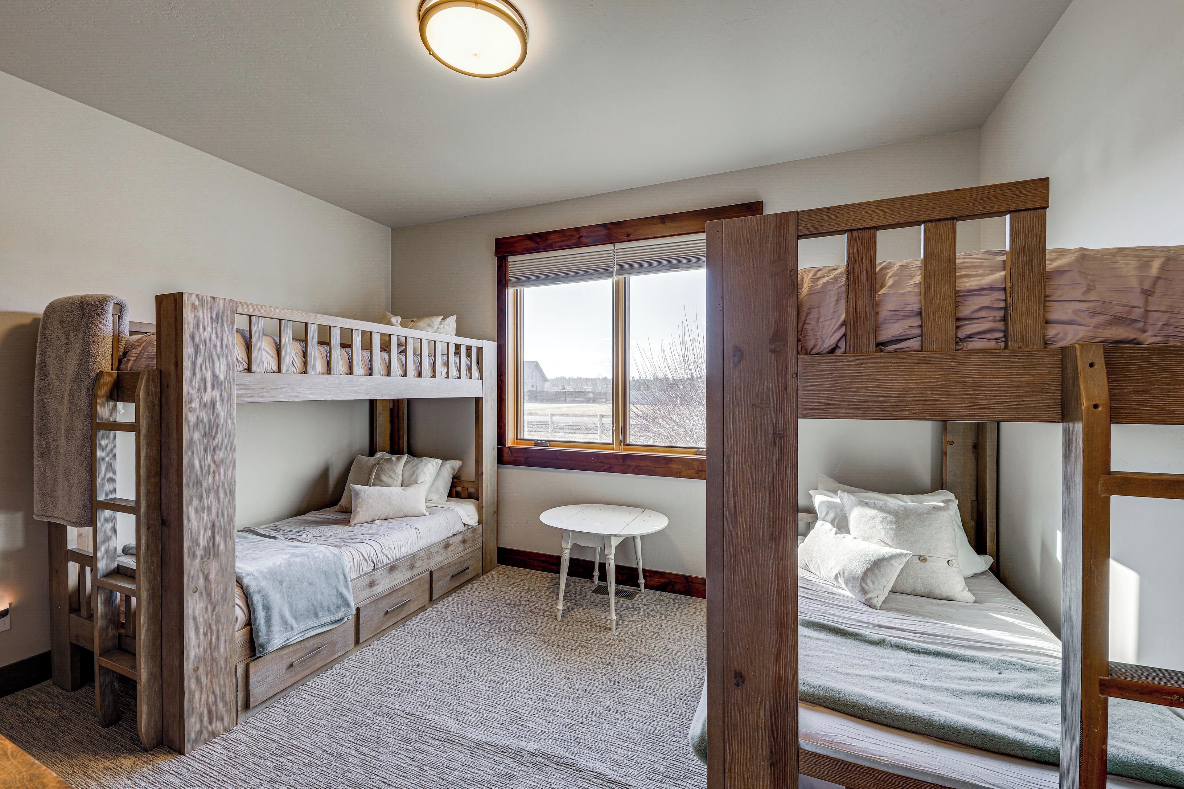 Habitación con literas, una mesita blanca y ventana con vistas.