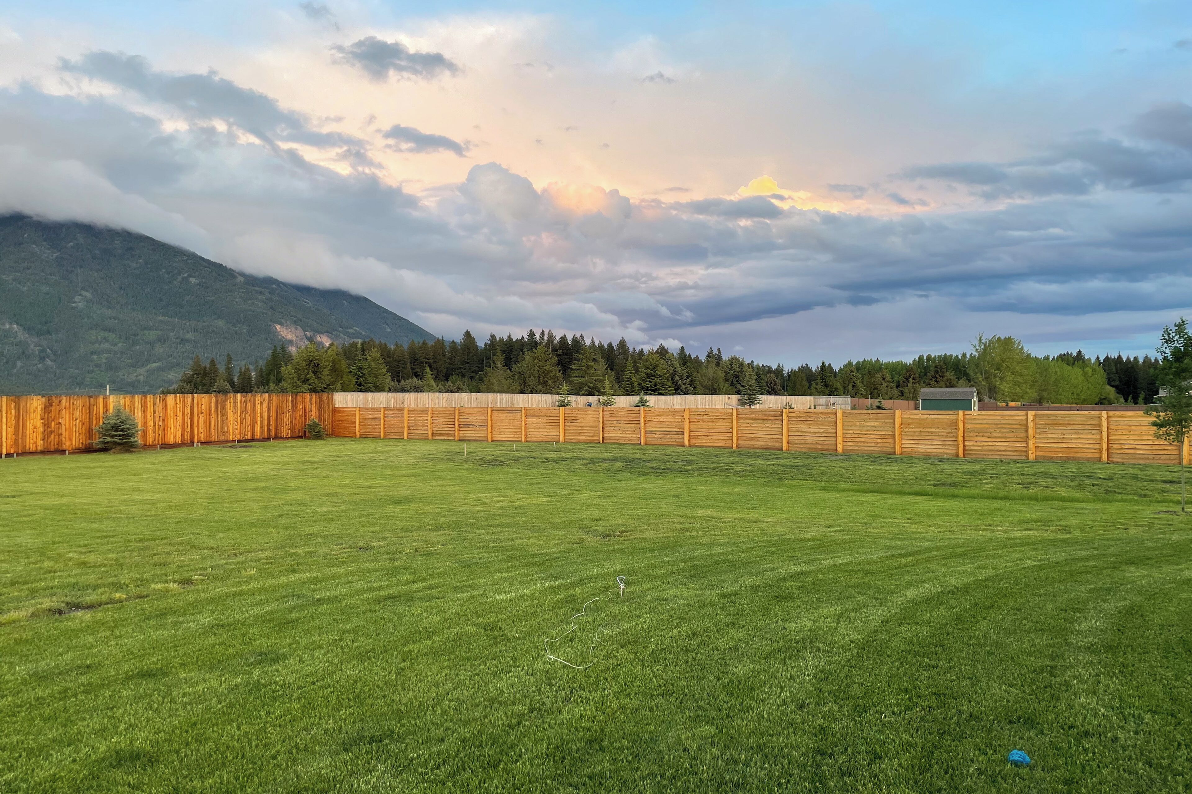 A grassy field with a wooden fence and a mountain in the background.