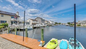 A wooden dock with kayaks, a marina with boats, and houses along a river. - Canal-front Backyard Oasis! Jersey Shore Retreat (Brick)