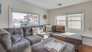 A living room with a sectional sofa, a wooden coffee table, and a wall-mounted compass decoration. - Canal-front Backyard Oasis! Jersey Shore Retreat (Brick)