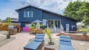 A blue house with a patio, outdoor seating, a barbecue grill, and a small water feature. - Canal-front Backyard Oasis! Jersey Shore Retreat (Brick)