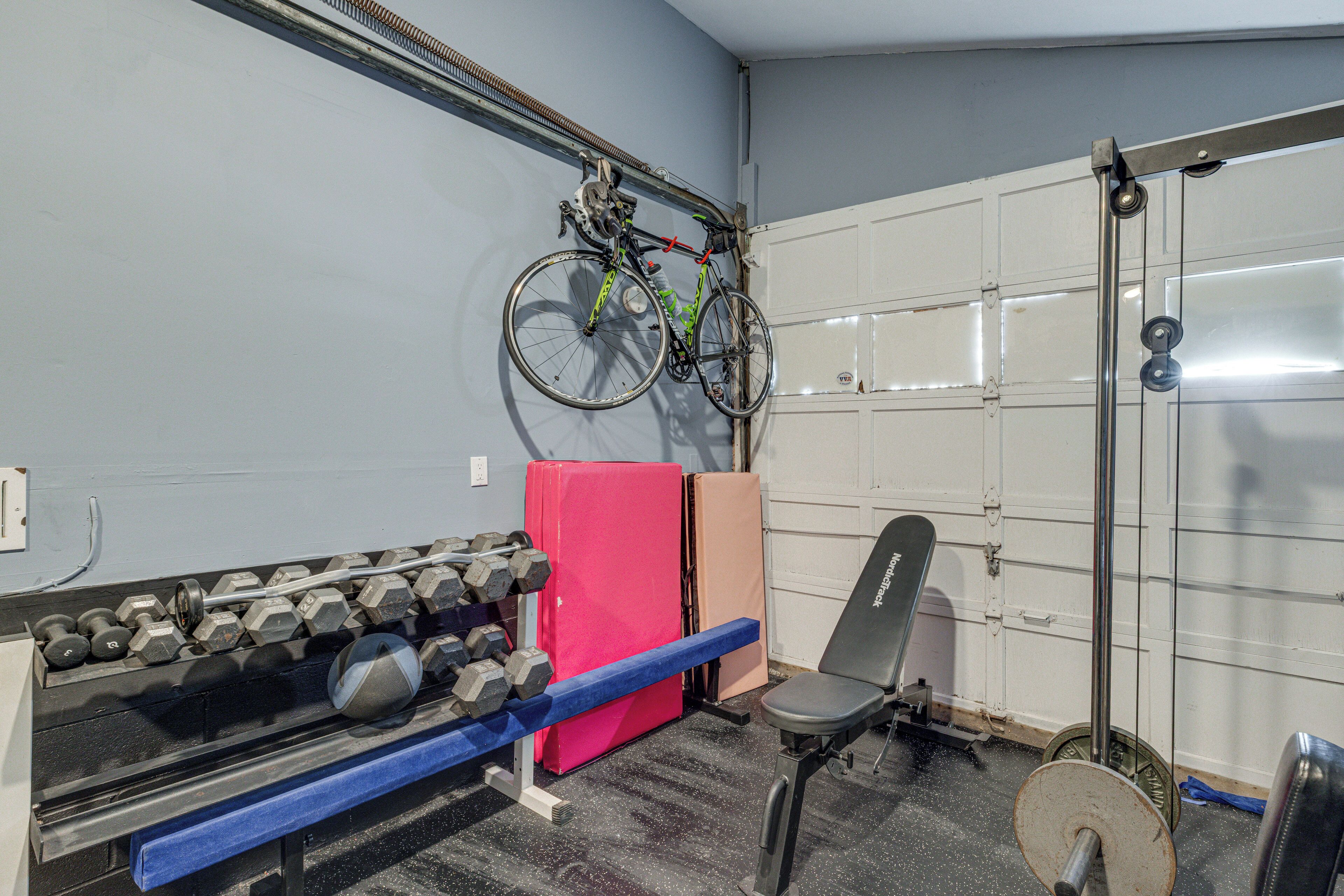 Un gimnasio con equipo de ejercicio, una bicicleta y una puerta.