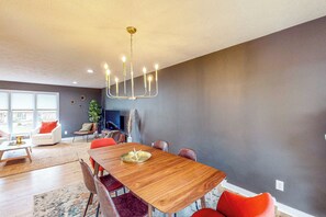 Ein moderner Essbereich mit einem Holztisch, roten Stühlen und einer Chandelüster.