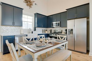 A modern kitchen with dark blue cabinets, stainless steel appliances, and a wooden dining table set for six. - Great for Boating & Fishing! Lake Greenwood Escape (Greenwood)