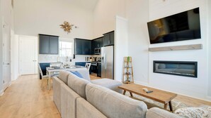 A modern kitchen with dark cabinets, a large TV, and a fireplace. - Great for Boating & Fishing! Lake Greenwood Escape (Greenwood)