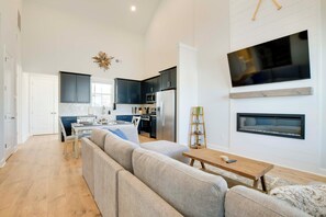 A modern kitchen with dark cabinets, a large TV, and a fireplace. - Great for Boating & Fishing! Lake Greenwood Escape (Greenwood)