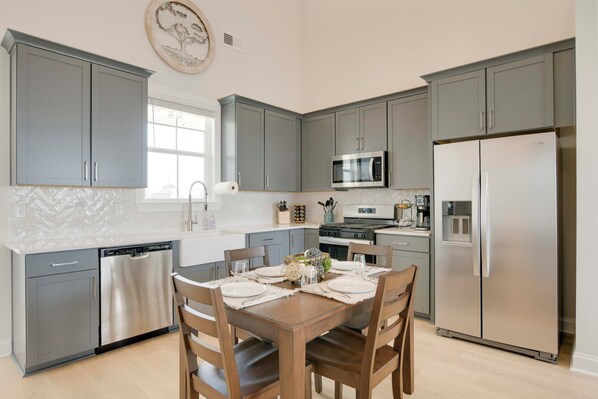 A modern kitchen with grey cabinets, stainless steel appliances, and a wooden dining table set for four. - Steps to Marina! Lake Greenwood Home w/ Patios (Greenwood)