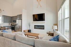 Ein geräumiges Wohnzimmer mit einer großen Couch, einem Couchtisch und einem Kamin.
