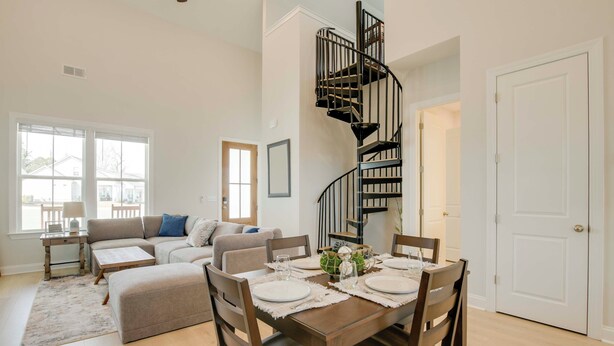 A dining area with a wooden table set for four, a spiral staircase, and a living room with a sofa and a coffee table. - Steps to Marina! Lake Greenwood Home w/ Patios (Greenwood)