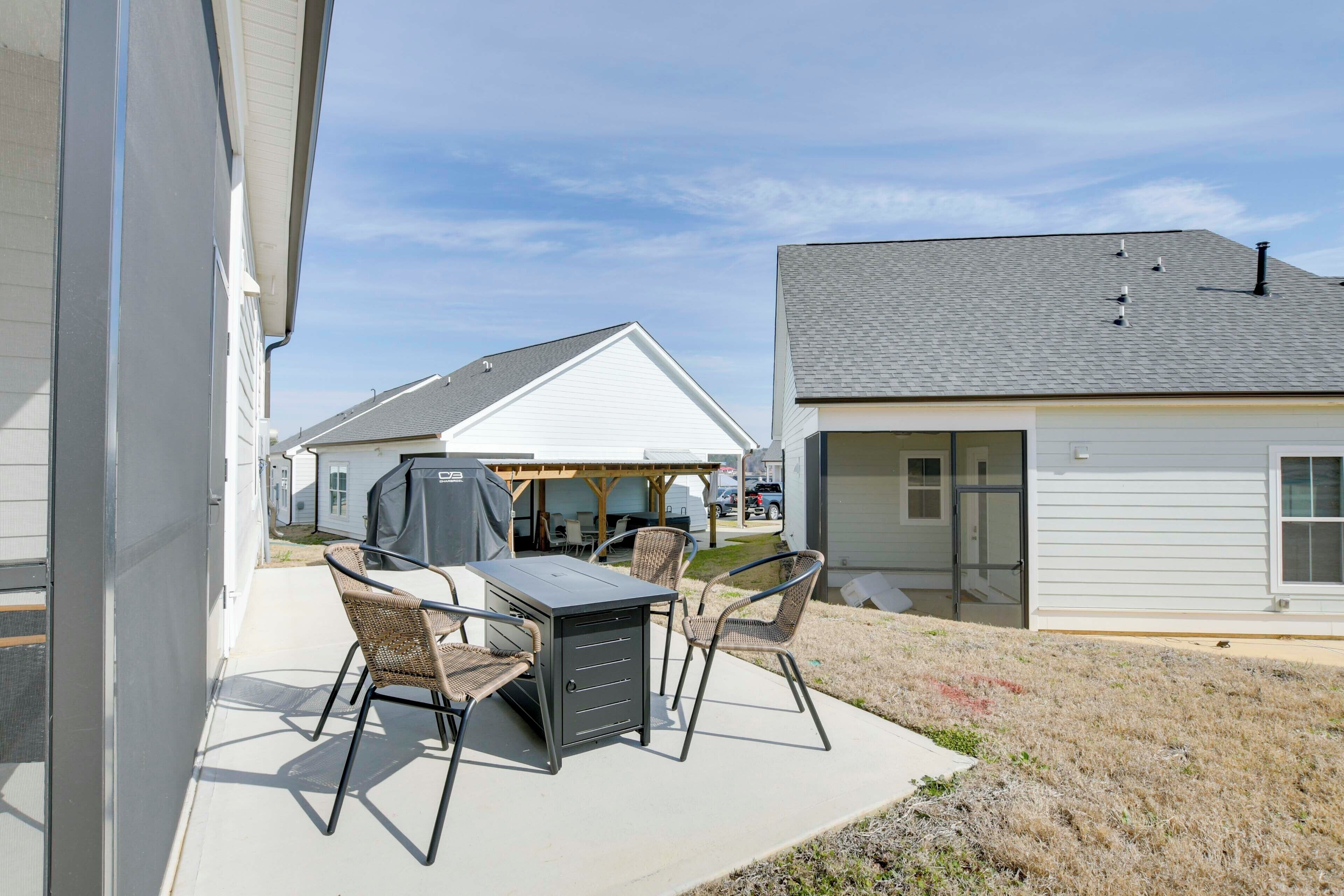 A patio with a table and chairs, a grill, and a covered area with tables and chairs.