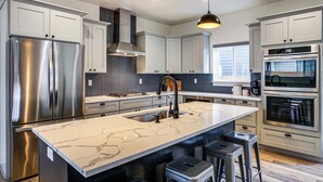 A modern kitchen with stainless steel appliances, a marble island, and pendant lighting. - 1 Mi to Lake Coeur D'alene: Pet-friendly Getaway (Coeur d'Alene)