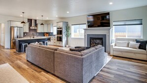 A modern kitchen with stainless steel appliances, a dining area with a large island, and a living room with a fireplace. - 1 Mi to Lake Coeur D'alene: Pet-friendly Getaway (Coeur d'Alene)