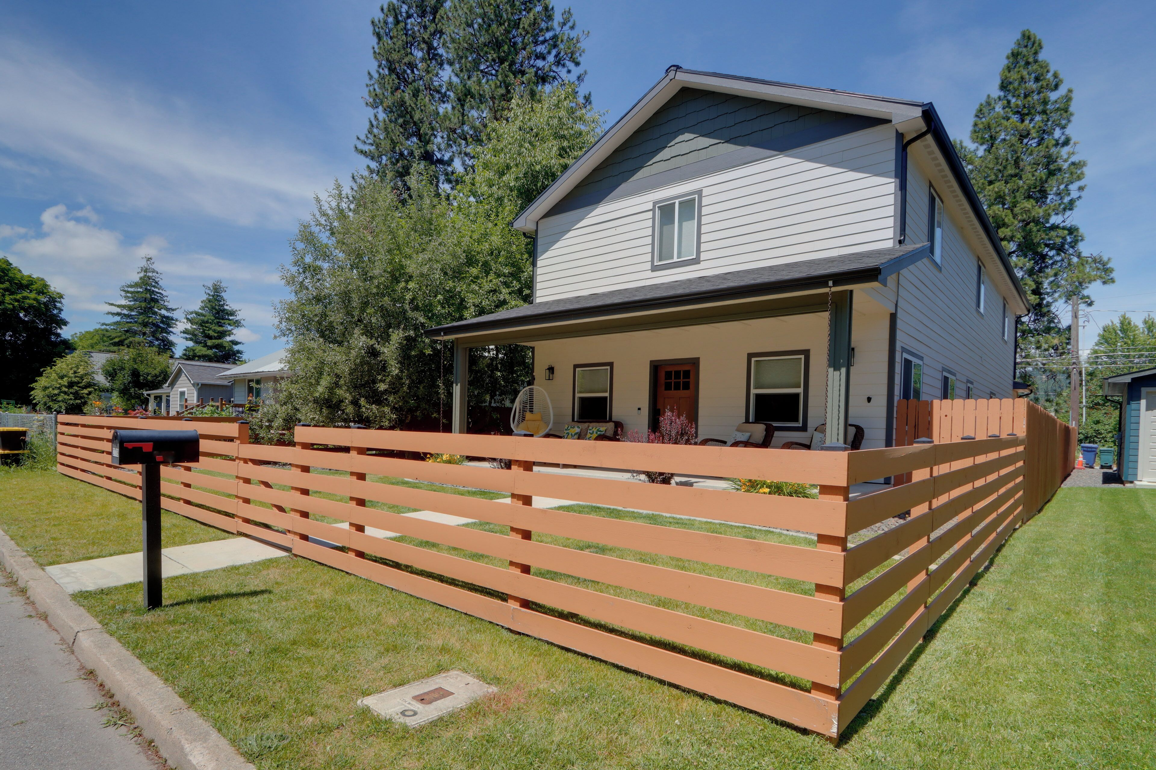 A two-story house with a front porch, a mailbox, and a wooden fence.