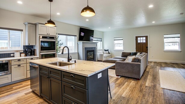 A spacious living area with a kitchen, a fireplace, and a large couch. - 1 Mi to Lake Coeur D'alene: Pet-friendly Getaway (Coeur d'Alene)