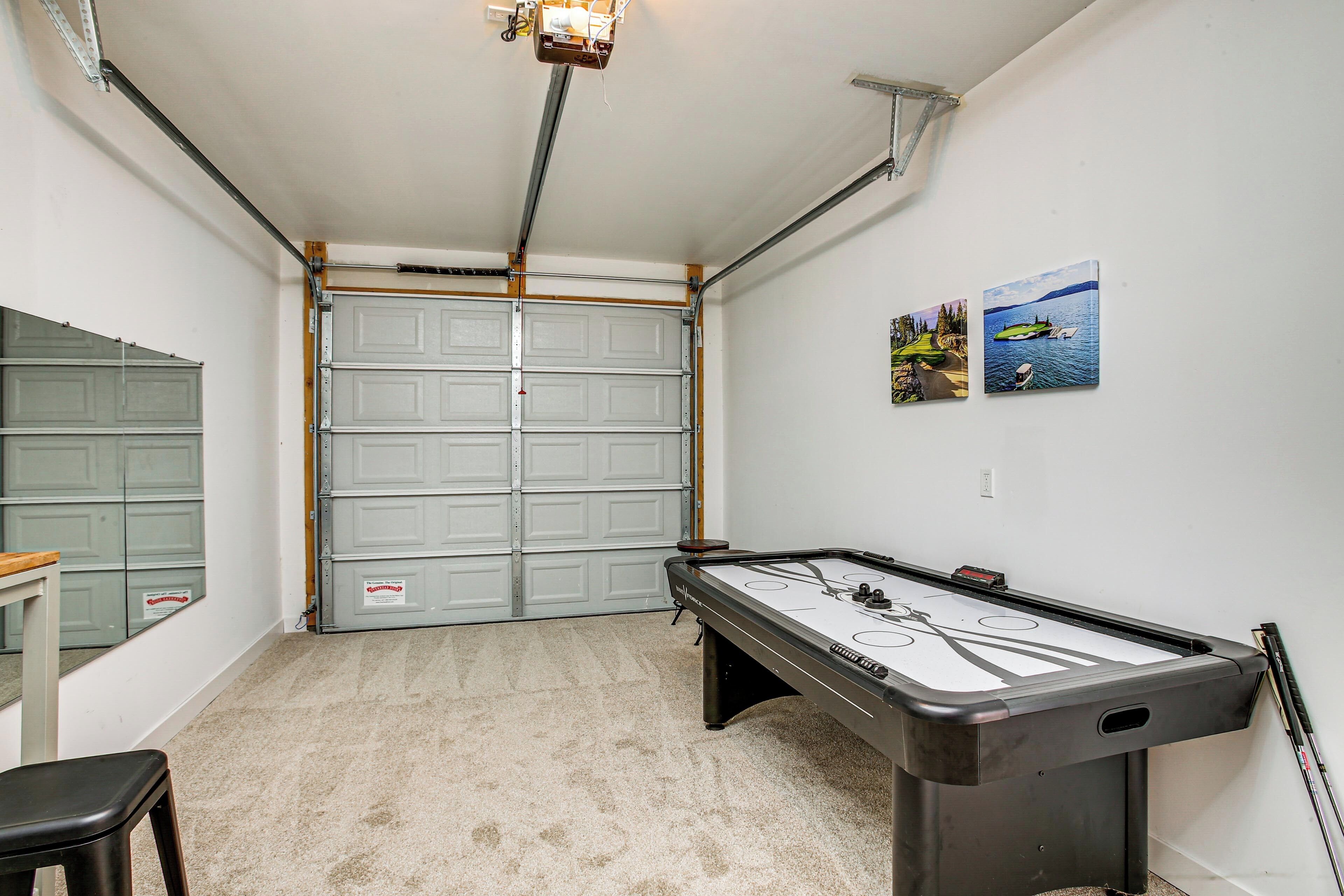 A room with a pool table, a glass table, a chair, and a garage door.