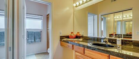 A bathroom with a vanity, sink, and mirror. There are lights above the mirror and a towel rack with towels.