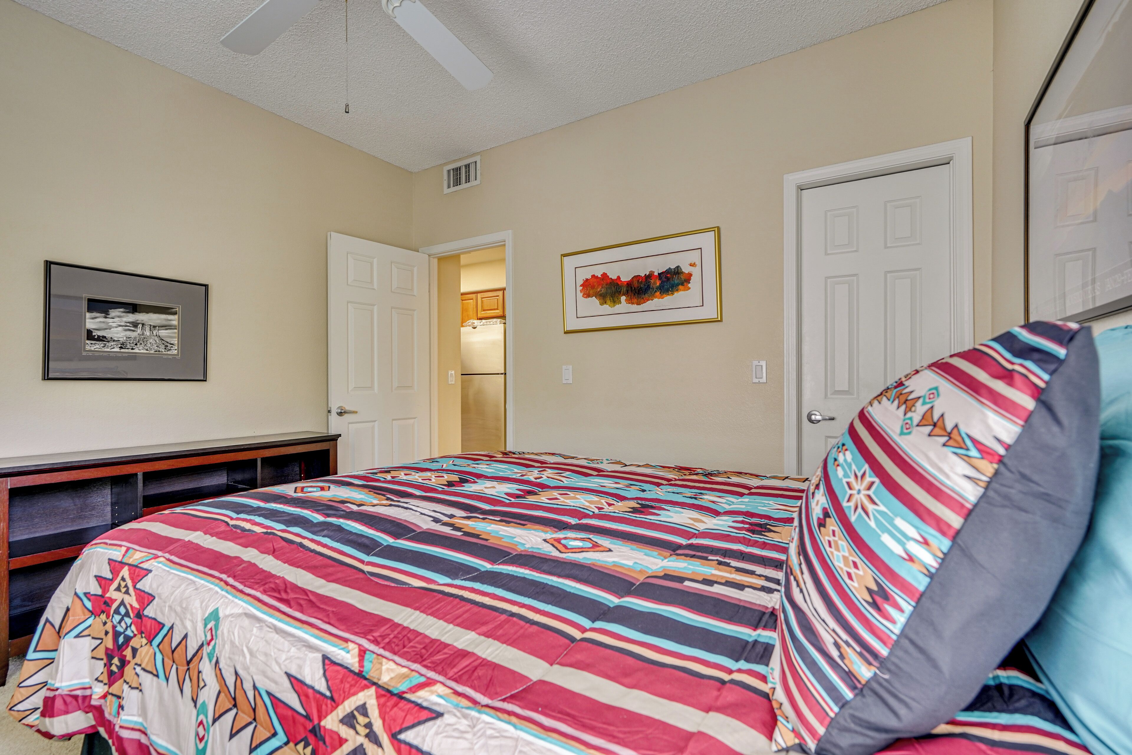 A bedroom with a large bed, a desk, and a door leading to a bathroom.