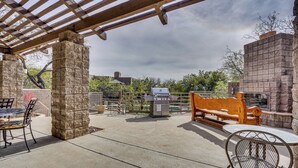 Un patio exterior con una parrilla, asientos y pilares de piedra.